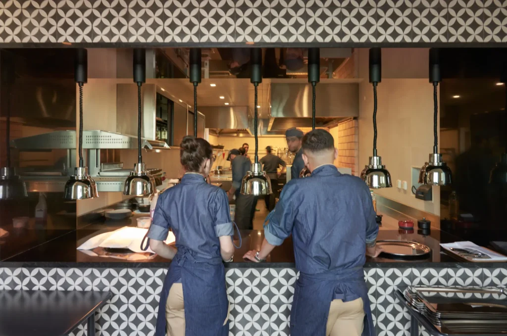 View of an open kitchen with chefs and waiters working